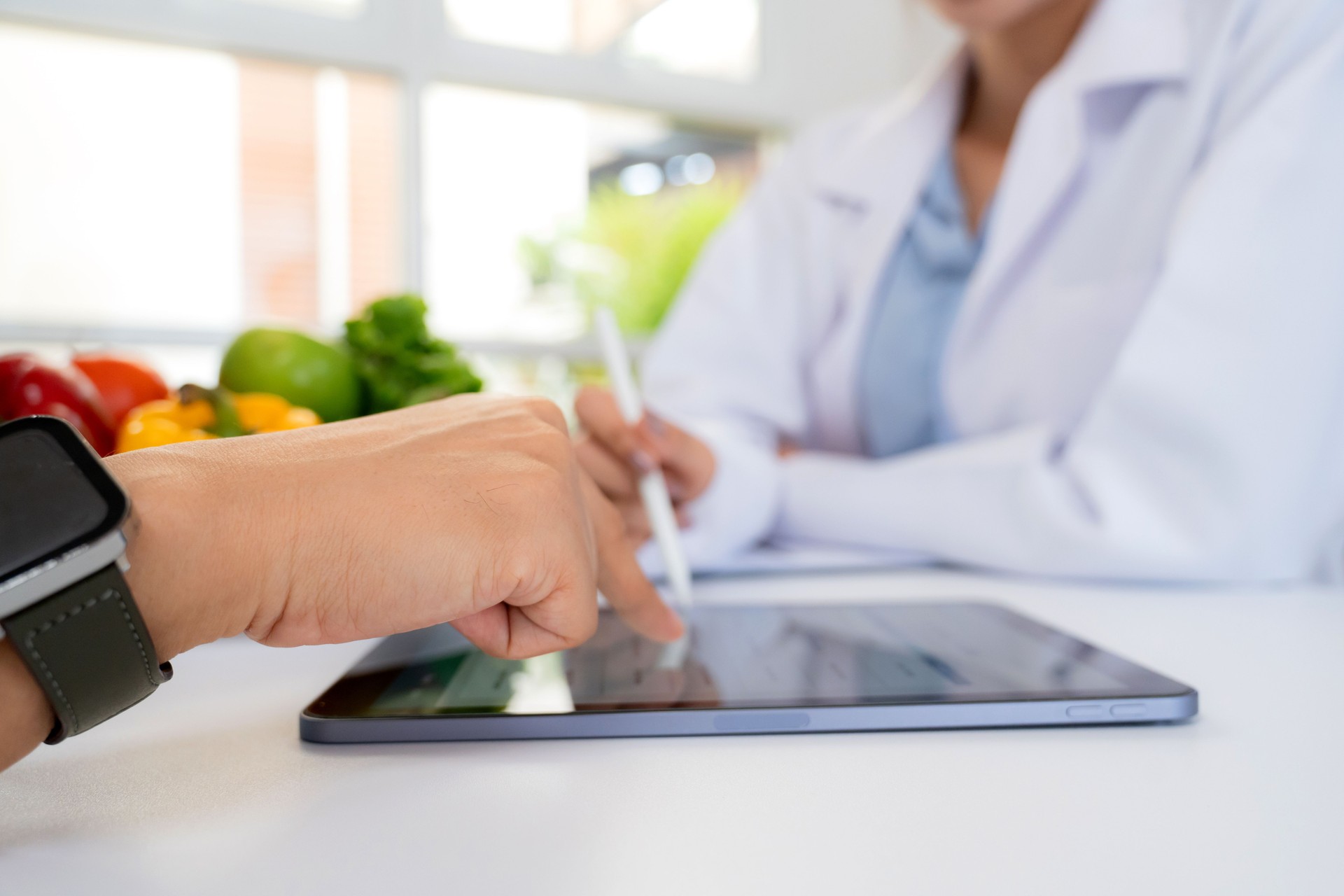 Asian nutritionist using tablet to explaining personalized meal plan with AI to patient during healthcare consultation, healthy lifestyle, woman dietitian showing nutrition plan with AI on tablet.