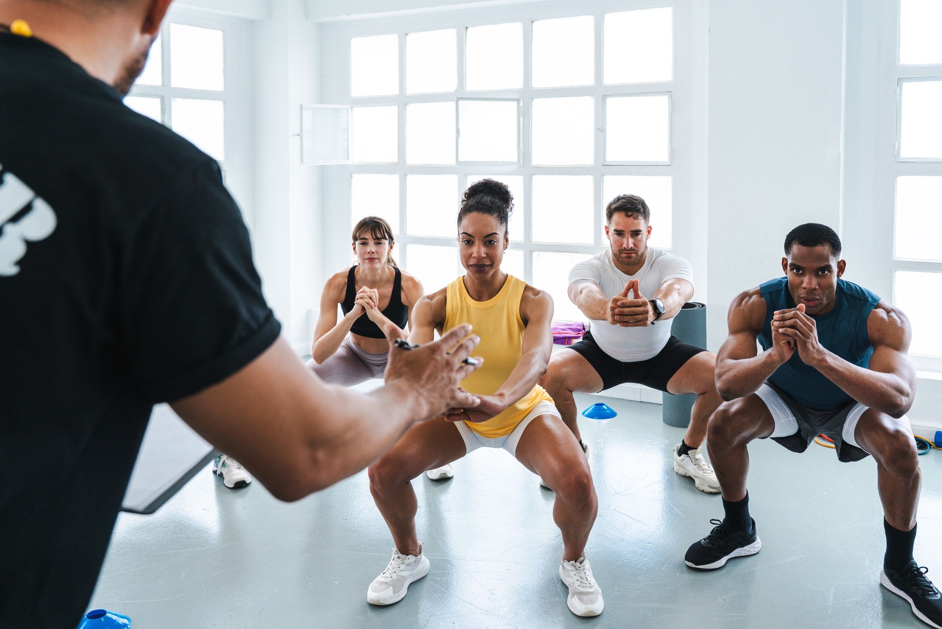 Trainer guiding athletes doing squats during functional training workout